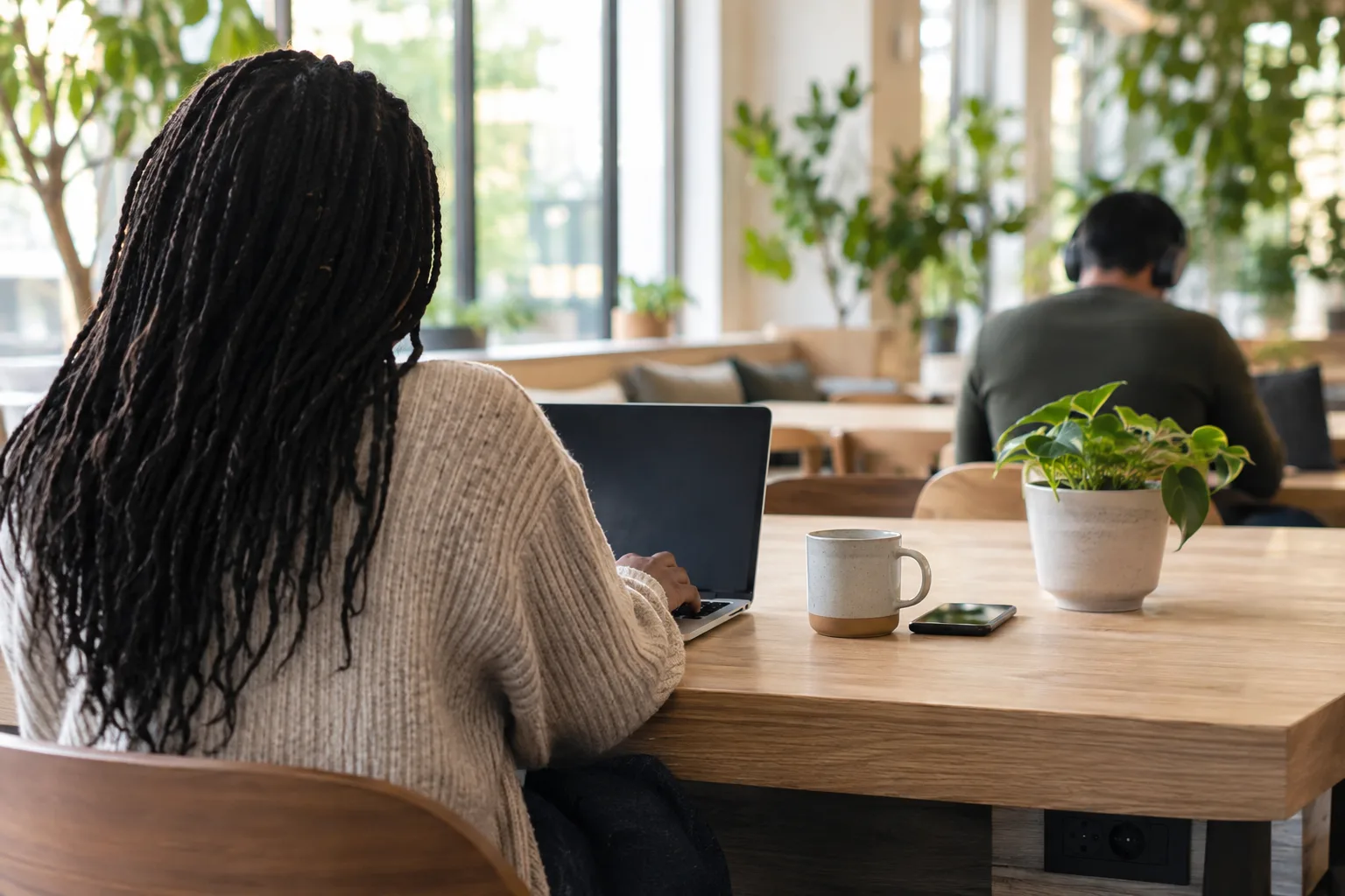 A bright coffee shop with spacious tables, power outlets, laptops, and quiet seating for a productive workday.